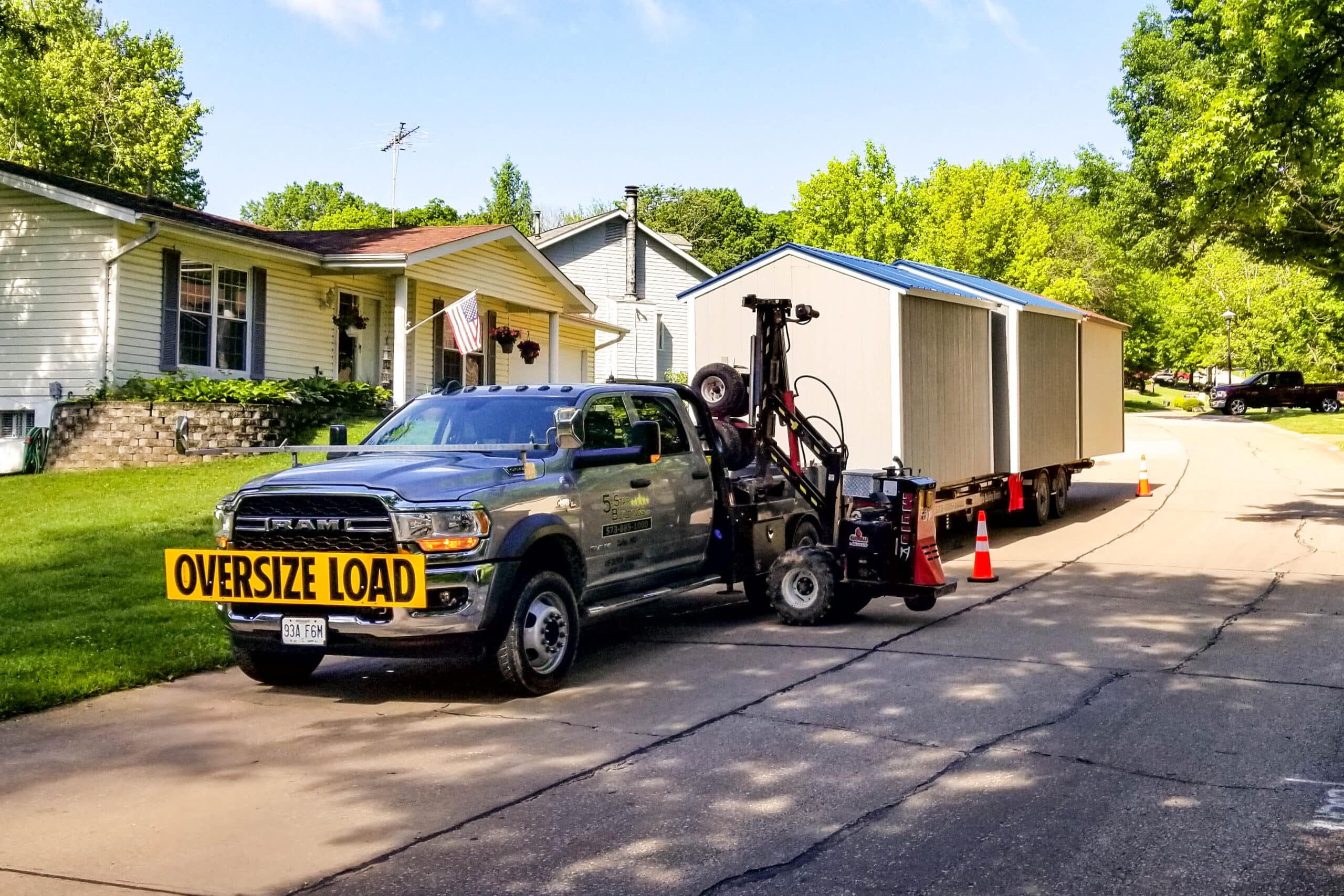 We deliver sheds to Sullivan MO - Gray pickup truck towing gray and white sheds to property private road flanked by sparse trees