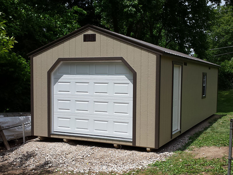 One of our navy blue storage buildings for sale in Sullivan MO - Blue siding with white overhead and side door and white -framed window and dark metal roof