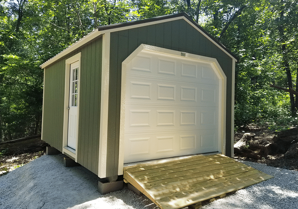 One of our navy blue storage buildings for sale in Sullivan MO - Blue siding with white overhead and side door and white -framed window and dark metal roof