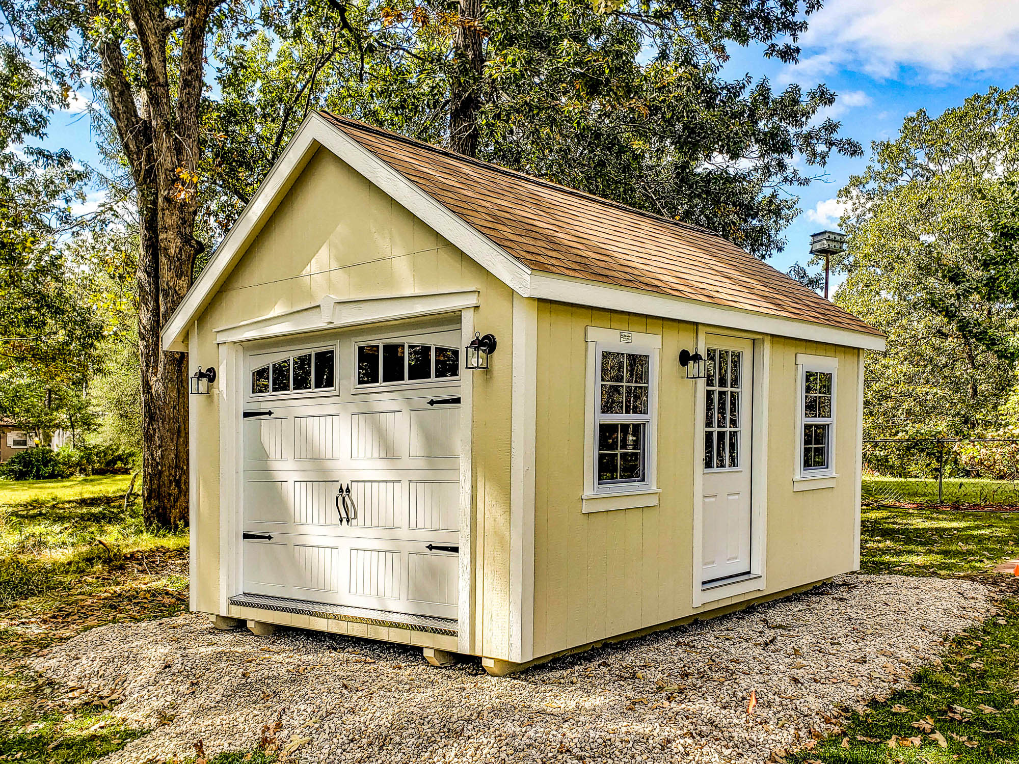 One of our navy blue storage buildings for sale in Sullivan MO - Blue siding with white overhead and side door and white -framed window and dark metal roof