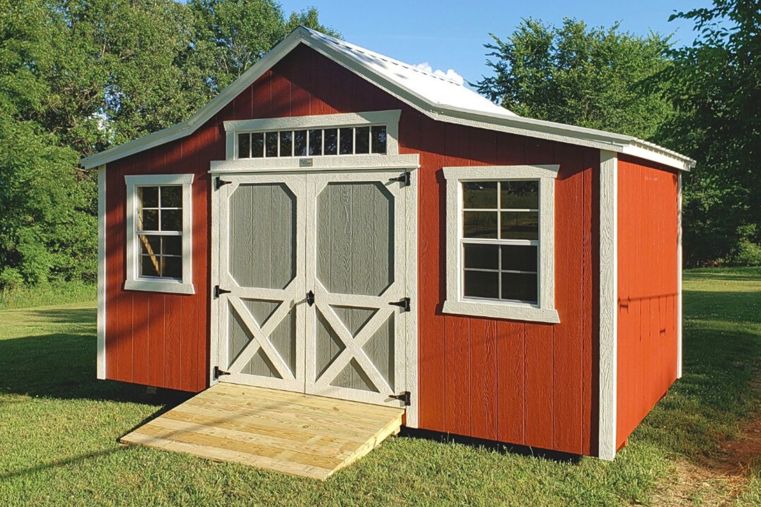 We deliver sheds to Sullivan MO - Gray pickup truck towing gray and white sheds to property private road flanked by sparse trees